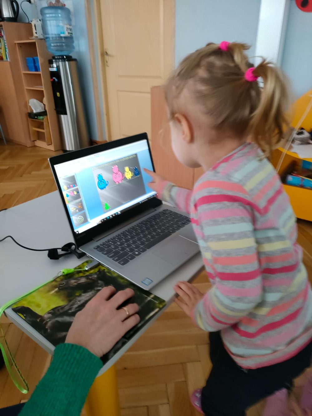 Dziewczynka pokazuje obrazek dinozaura na ekranie komputera