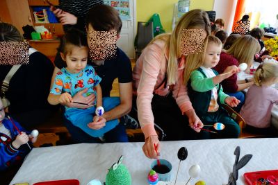 Rodzice z dziećmi malują wielkanocne styropianowe jajka