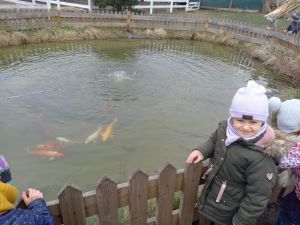 dziewczynka stoi przy oczku z rybami