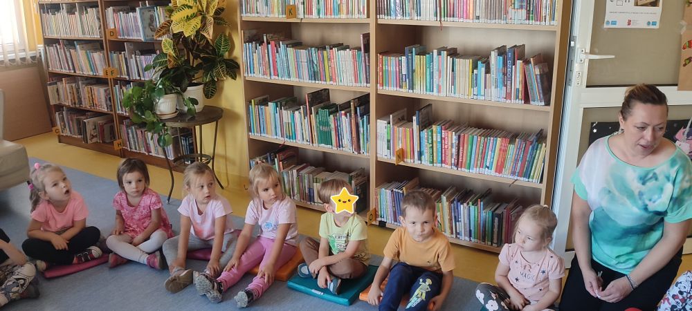 Dzieci z grupy 3 siedzą w kole i słuchają Pani z biblioteki