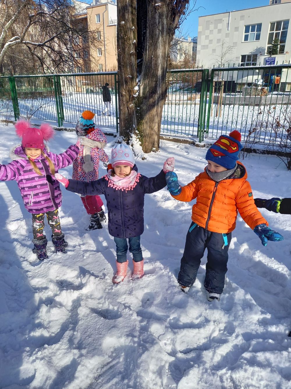 Dzieci bawią się śniegiem w ogrodzie przedszkolnym