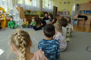 Dzieci siedzą na dywanie, a rodzic czyta książkę
