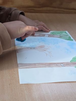 Dziecko maluje tło niebieską farbą