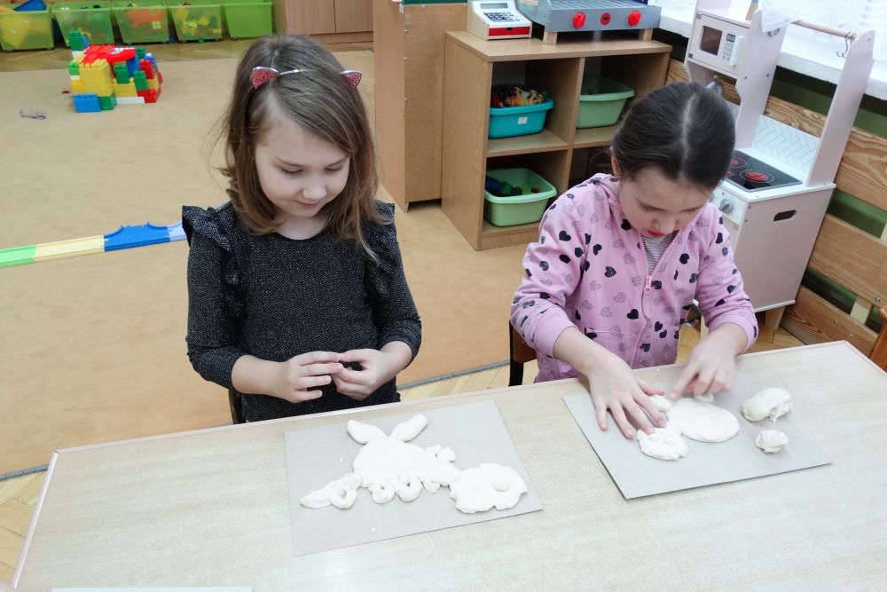 Dwie dziewczynki robią dinozaury z masy solnej