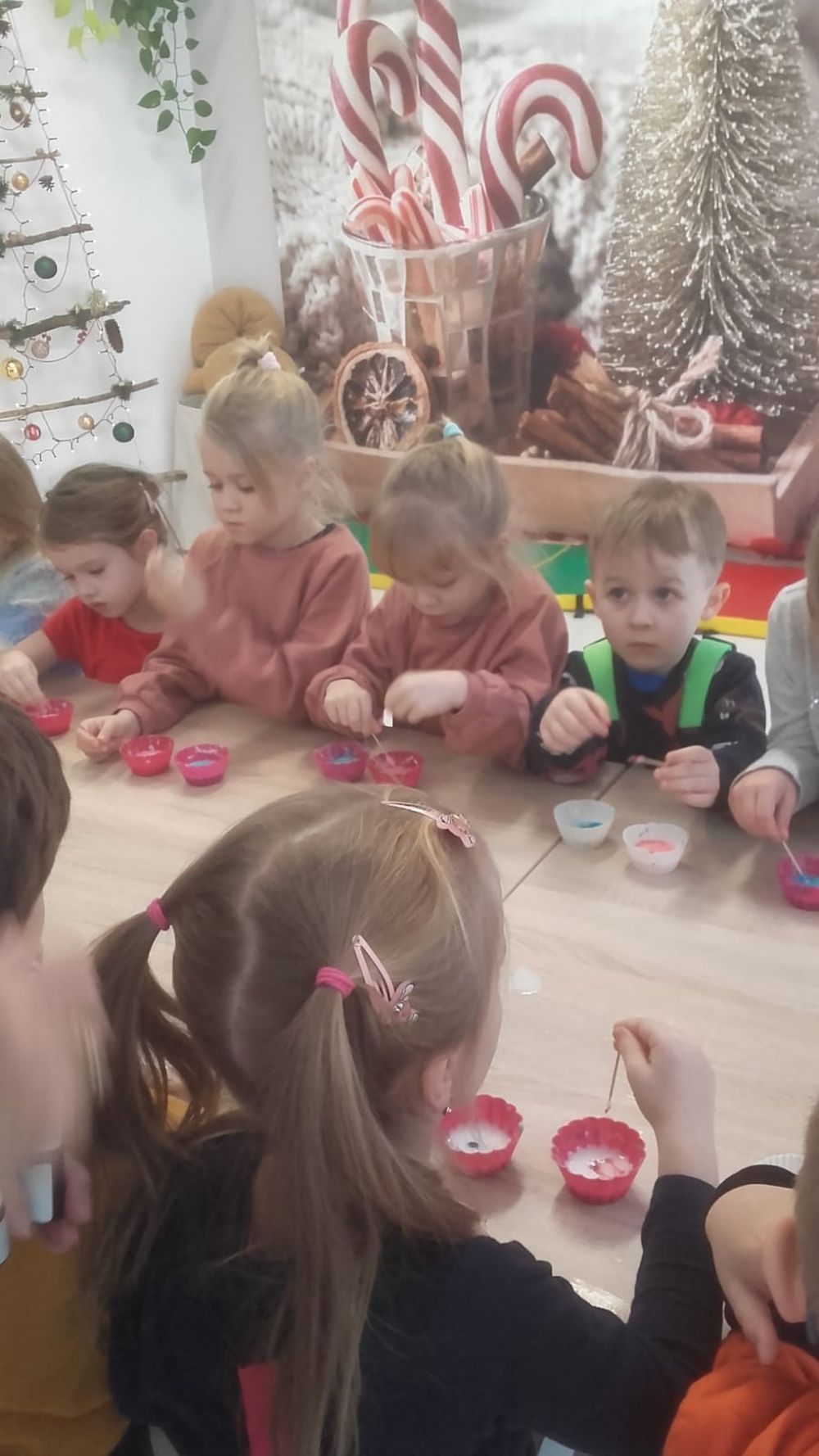 Dzieci stoją przy stole i robią kolorowe mydełka