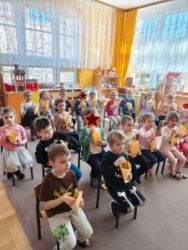 Dzieci siedzą na krzesełkach i oglądają bajkę
