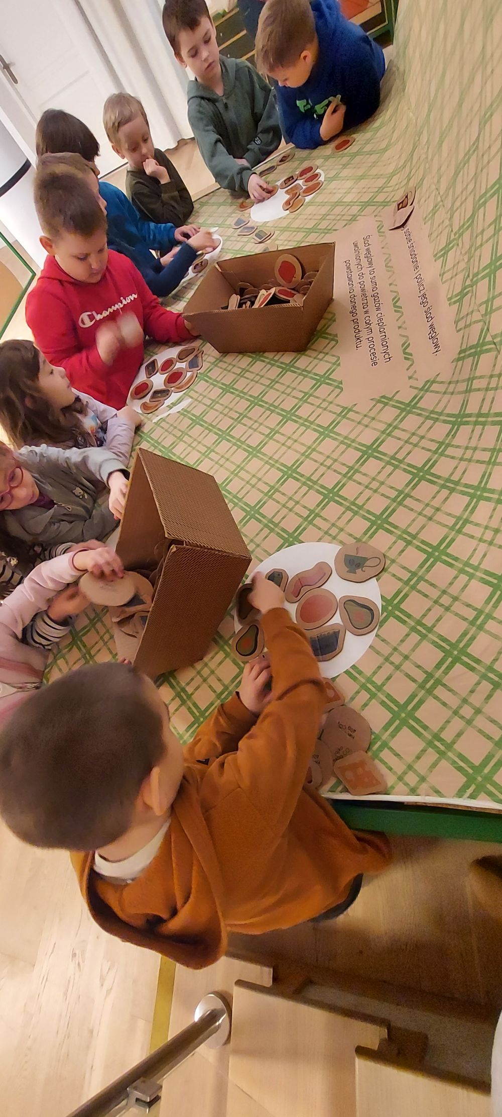 Dzieci wybierają kartonowe produkty i tworzą z nich na talerzach zdrowe śniadanie