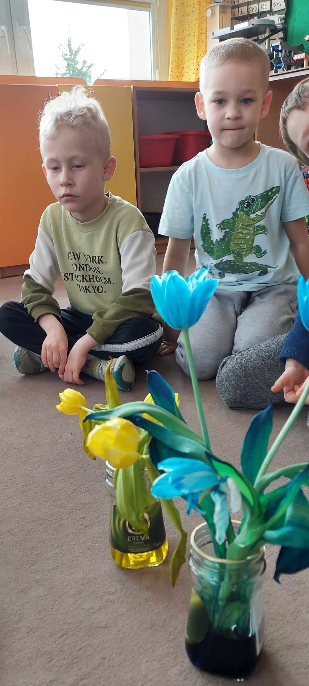 Dzieci oglądają zabarwione na niebiesko i żółto tulipany