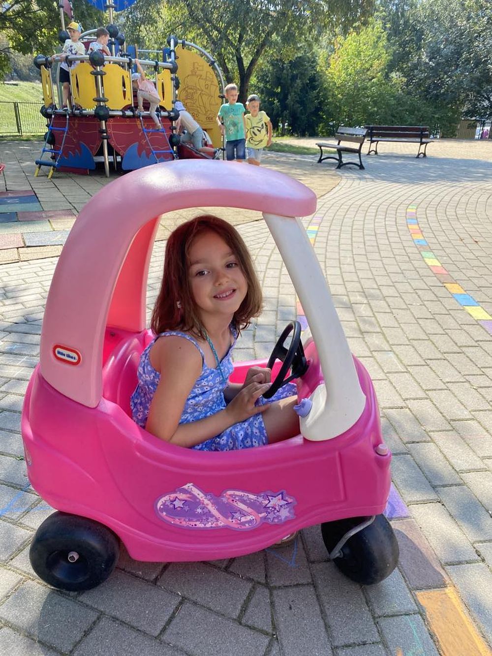 Dziewczynka na placu zabaw siedzi w zabawkowym samochodzie
