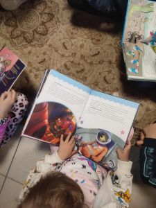 Dzieci siedzą na dywanie i czytają książki