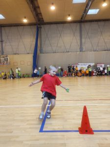 Chłopiec biegnie na hali sportowej ubrana w strój sportowy 