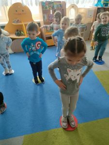 Dzieci stoją na kolorowych dyskach leżących na dywanie