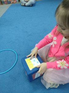 Dziewczynka siedzi na dywanie i liczy kropki na kostce