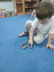 Chłopiec liczy orzechy położone w ringu na dywanie