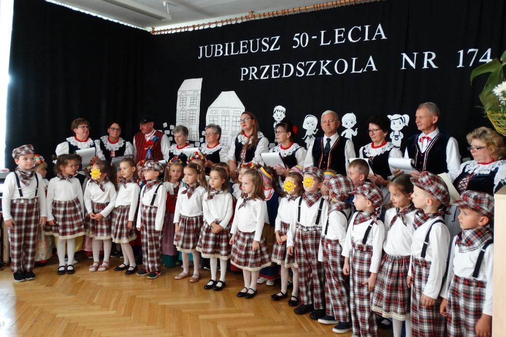 Dzieci ubrane w stroje ludowe oraz Dorośli z zespołu podbielanki ubrani w stroje ludowe.
