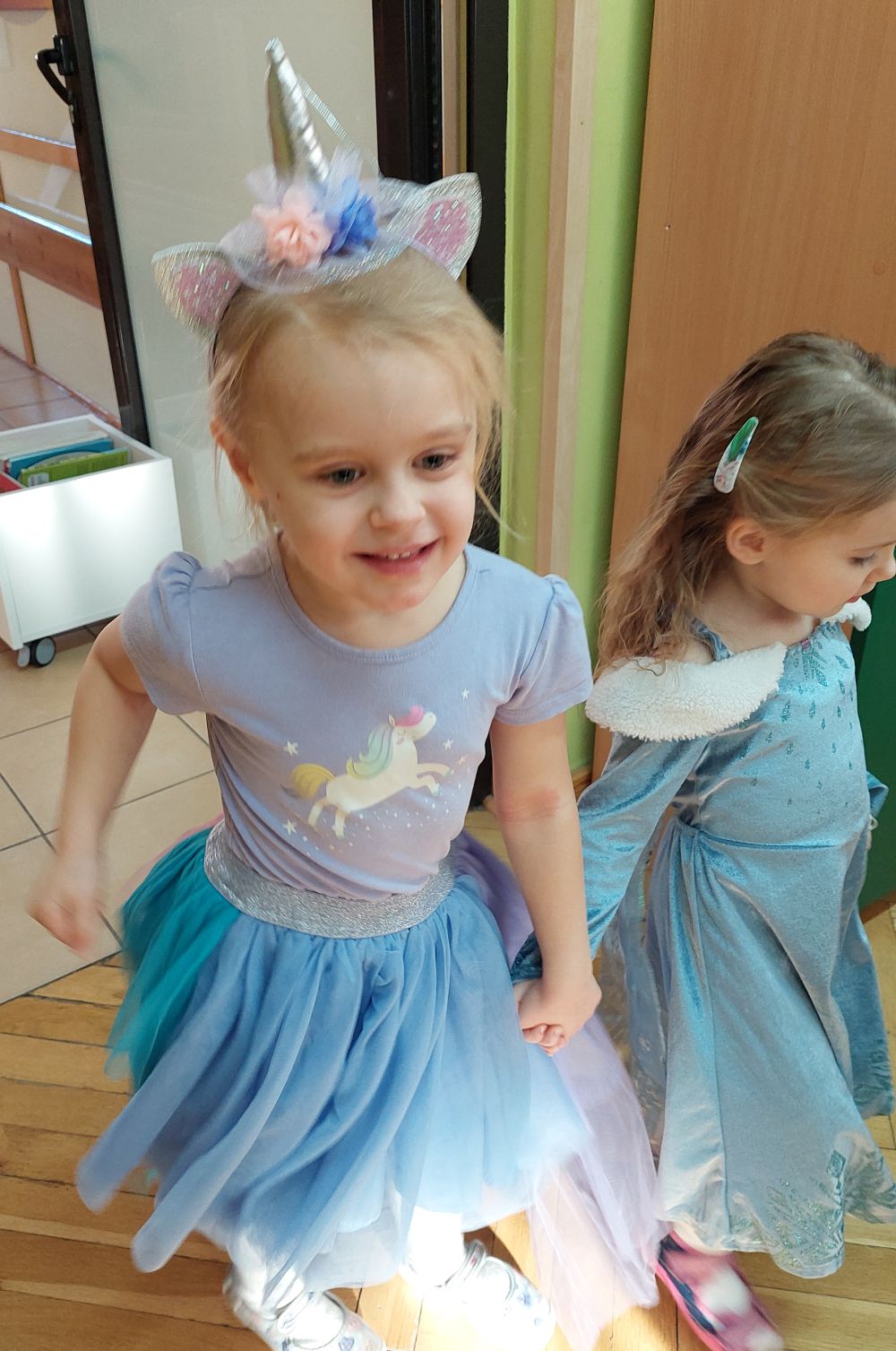 Dziewczynka w stroju jednorożca tańczy z dziewczynką w stroju księżniczki