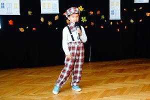 Zdjęcie przedstawia chłopca ubranego w kraciaste spodnie, białą bluzkę, muszkę w kratkę i kaszkiet w kratkę.