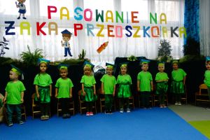 Dzieci ubrane na zielono stoją i śpiewają piosenkę