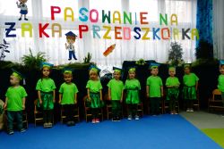 Dzieci ubrane na zielono stoją i śpiewają piosenkę