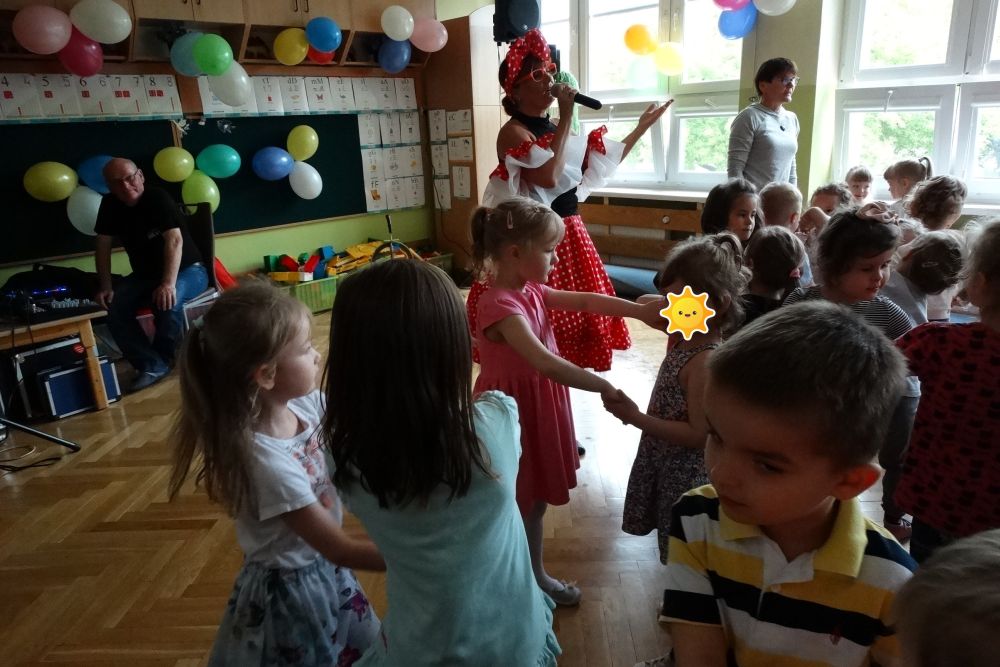 Dzieci tańczą trzymając się za ręce, podczas tańców z okazji dnia dziecka