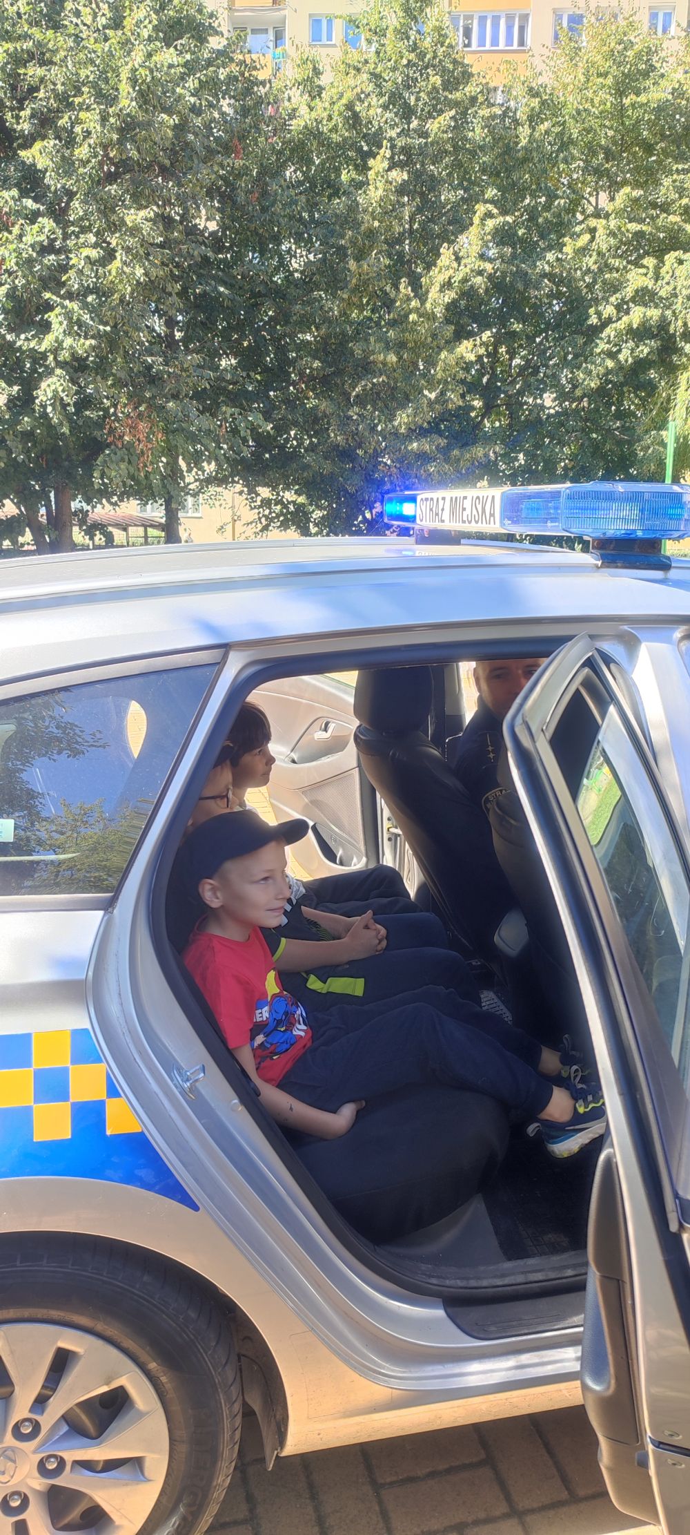 Dzieci siedzą w samochodzie Straży miejskiej