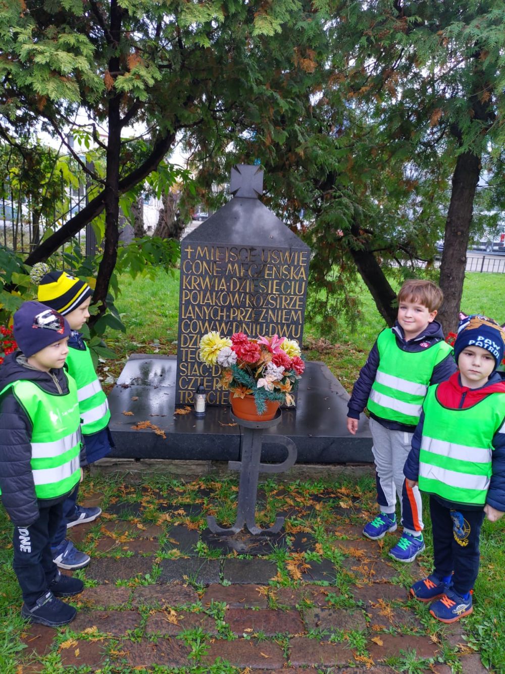 Czterech chłopców stoi przed pomnikiem poległych w walce.
