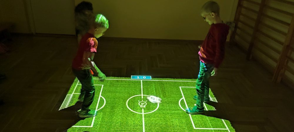 Dwóch chłopców gra w piłkę nożną na magicznym dywanie