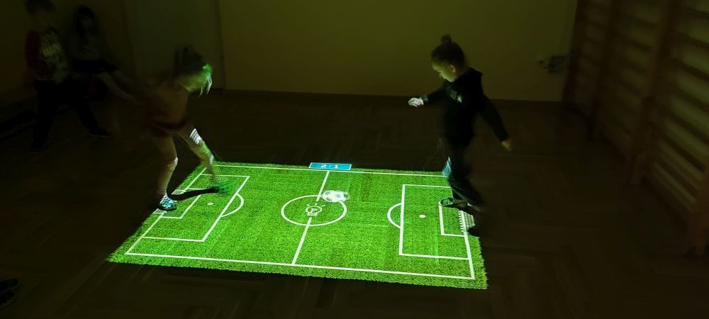 Dwie dziewczynki grają w piłkę nożną na magicznym dywanie