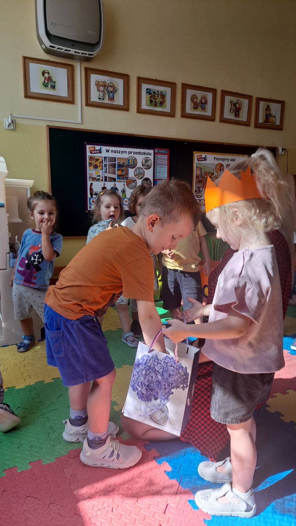 Dziewczynka w koronie rozdaje cukierki dzieciom z grupy