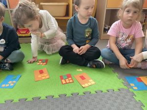 Dzieci układa kwadratowe kartoniki i papierowych prostokątach