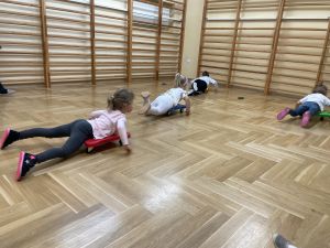 Dzieci jadą na deskorolkach gimnastycznych w sali gimnastycznej