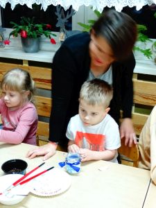 Dzieci ze swoimi rodzicami dekorują pierniczki