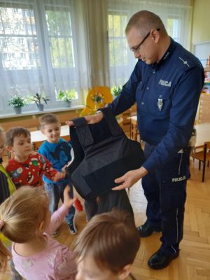 Policjant pokazuje dzieciom kamizelkę kuloodporną