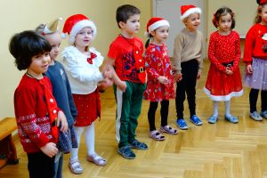 Dzieci stoją w półkolu i śpiewają Mikołajowi piosenkę