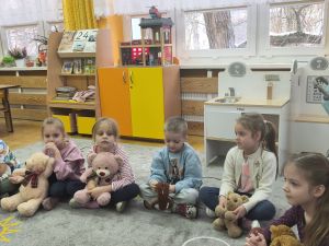 Dzieci siedzą w kole ze swoimi misiami