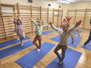 Dzieci stoją na macie w pozycji drzewa