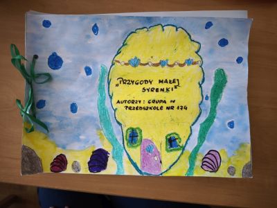 Obrazek zrobiony przez dziecko. Strona tytułowa książki, na obrazku domek małej syrenki w oceanie.