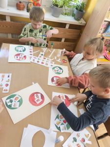 Dzieci przyklejają wycięte obrazki na kolorowych talerzach