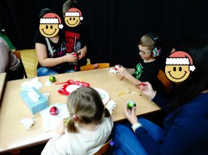 Dzieci ze swoimi rodzicami ozdabiają bombki