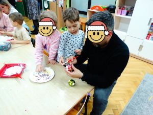 Dzieci ze swoimi rodzicami ozdabiają bombki