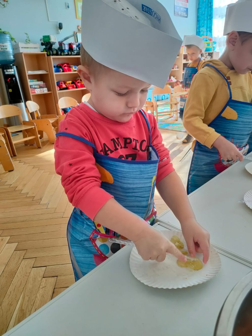 Chłopiec w stroju kucharza kroi warzywa