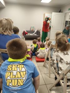 Dzieci siedzą na krzesłach i oglądają występ