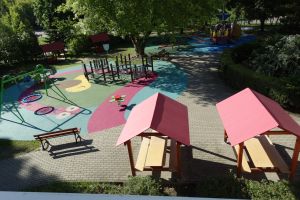 Zdjęcie nowego placu zabaw, na którym widać domki, huśtawkę, tor do przechodzenia 